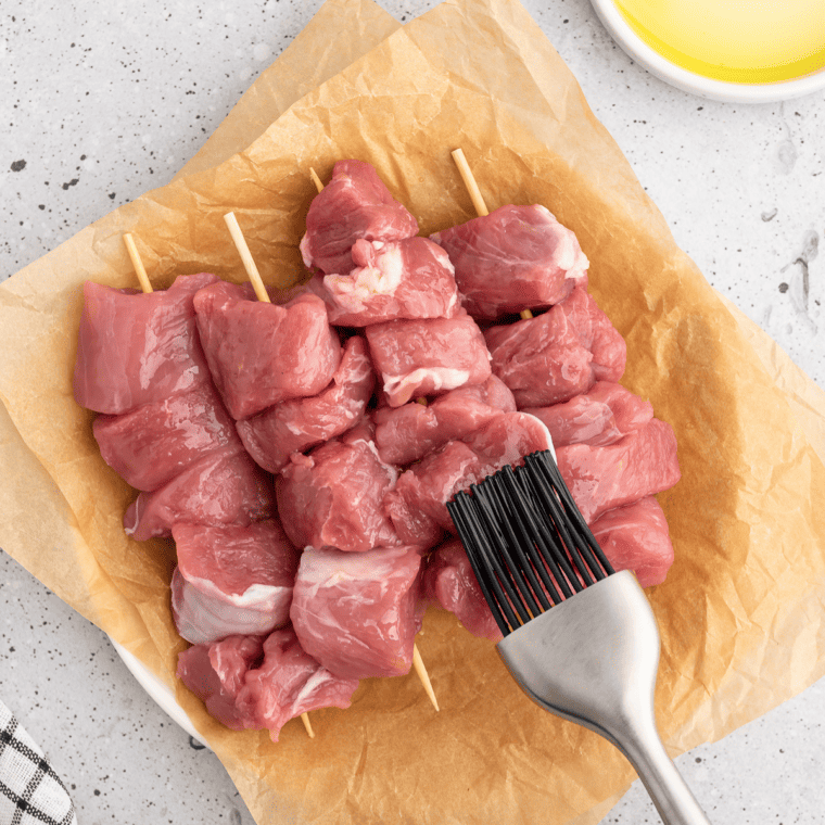 Pork tenderloin pieces on skewers brushed with oil before adding jerk seasoning