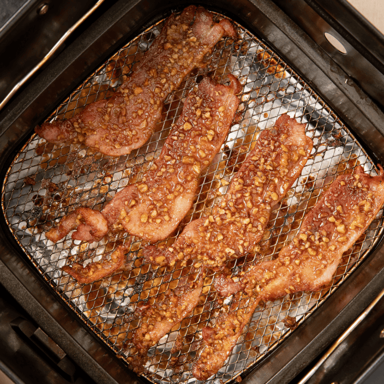 Air fryer praline bacon cooking with the sugar coating bubbling and caramelized