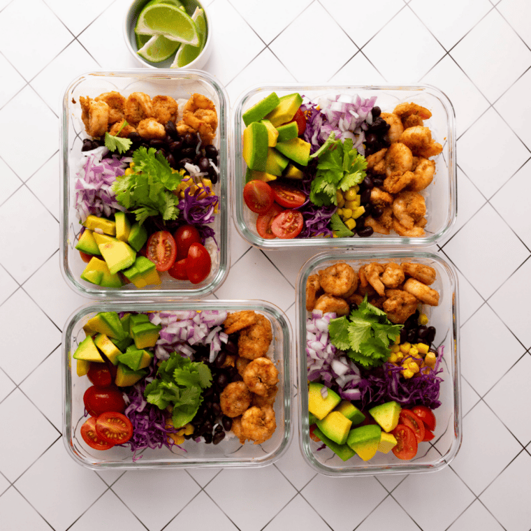 Cilantro-lime crema drizzled over shrimp in a colorful taco bowl with mango, cabbage, and a lime wedge
