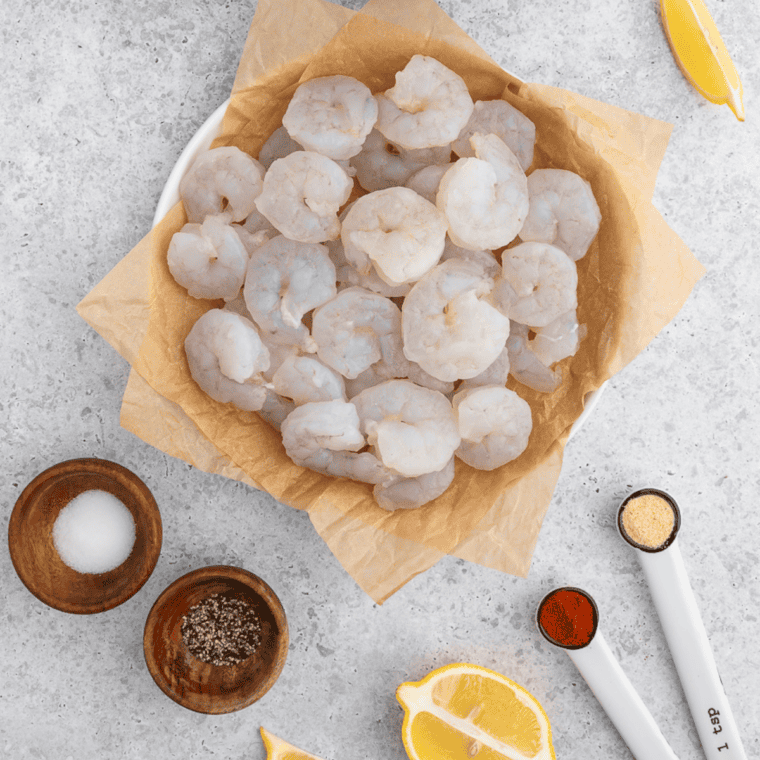 Ingredients for air fryer shrimp taco bowls including raw shrimp, jasmine rice, mango, purple cabbage, corn, pickled red onions, lime, garlic, honey, and cilantro