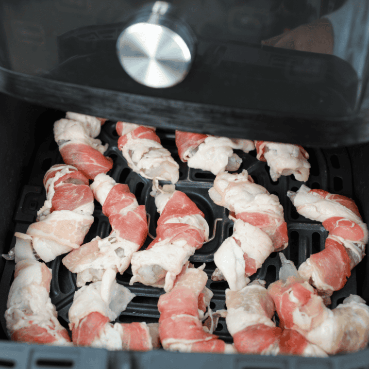 Crispy bacon wrapped shrimp in a single layer in an air fryer basket