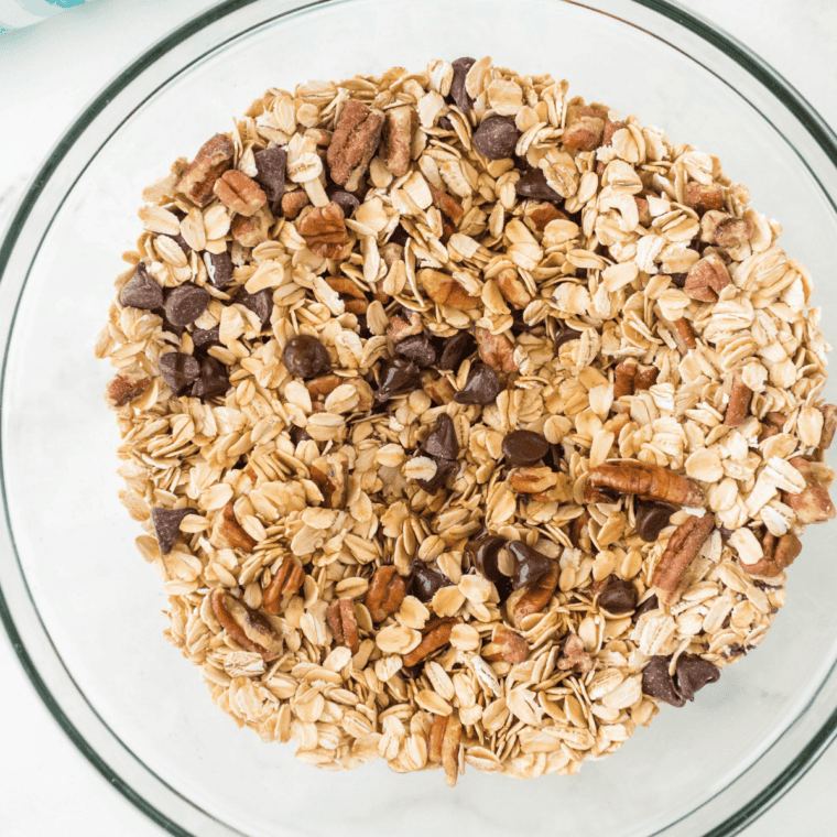 Dry granola ingredients oats, pecans and cinnamon mixed in a large bowl