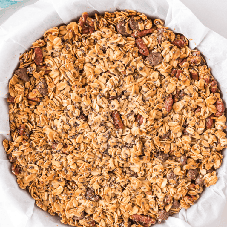 Maple pecan granola baking golden brown on a sheet pan in the oven