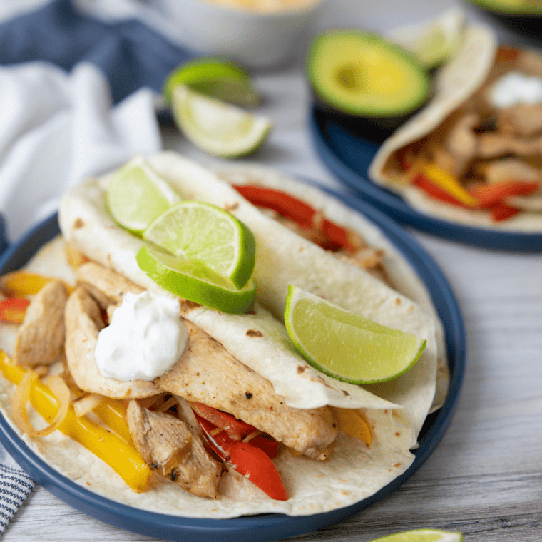 Blackstone chicken fajitas piled into warm tortillas with toppings, ready to serve