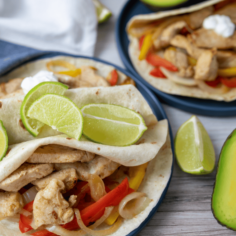 Plate of Blackstone chicken fajitas with charred peppers, onions, and warm tortillas