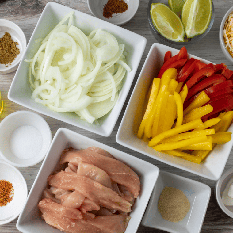 Raw ingredients for Blackstone chicken fajitas including chicken, bell peppers, onion, and spices