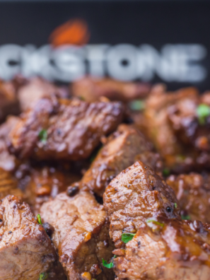 Sizzling Blackstone steak bites cooked on a griddle with garlic butter and seasoning.