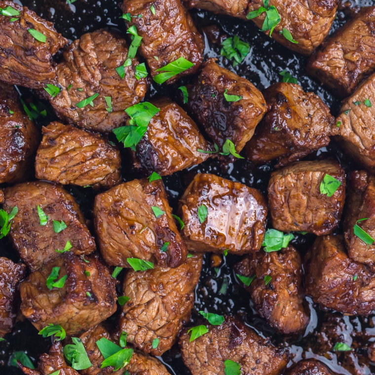 Finished garlic butter steak bites topped with fresh parsley, resting before serving