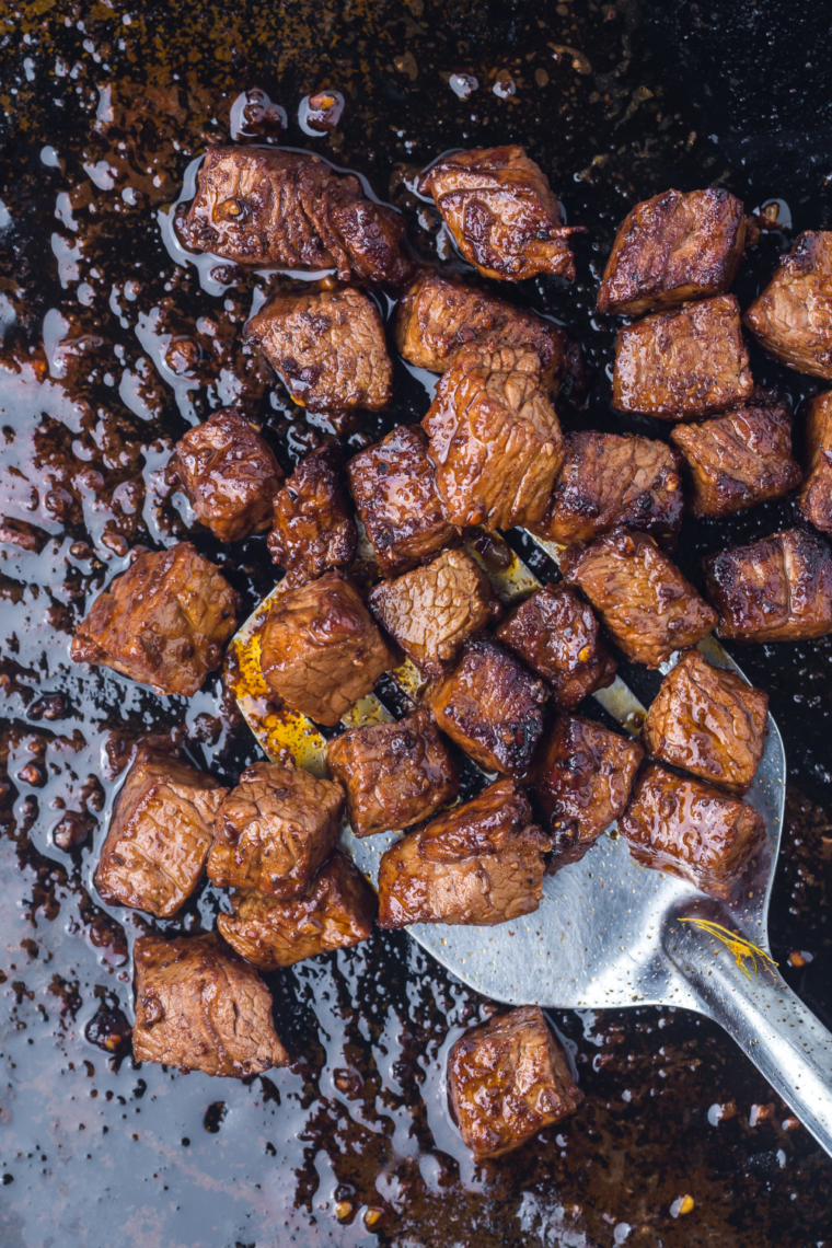 Sizzling Blackstone steak bites cooked on a griddle with garlic butter and seasoning.