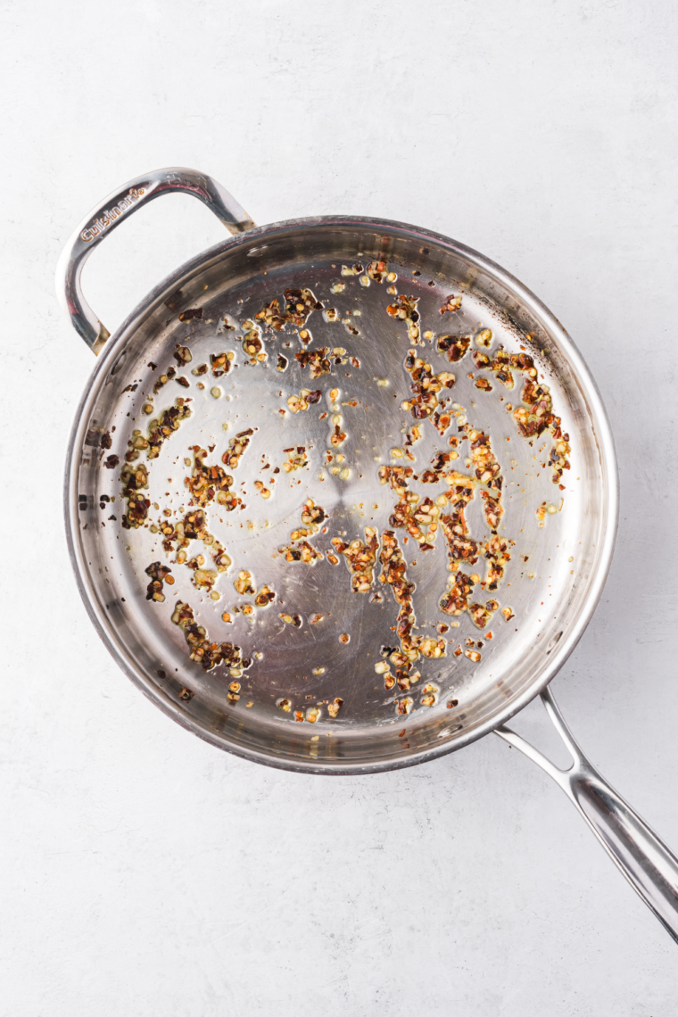 Dried herbs and spices blooming in warm olive oil in a small saucepan