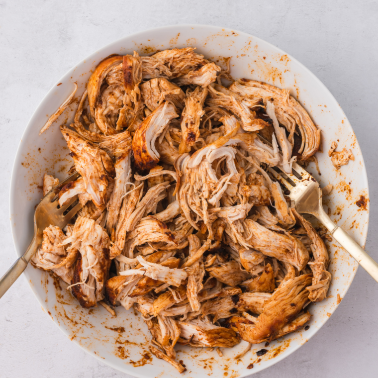 Homemade chicken taco seasoning sprinkled over cooked shredded chicken in a skillet.