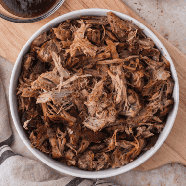 Shredded smoked pulled pork in a white bowl seasoned with copycat Jack Daniel's pork rub