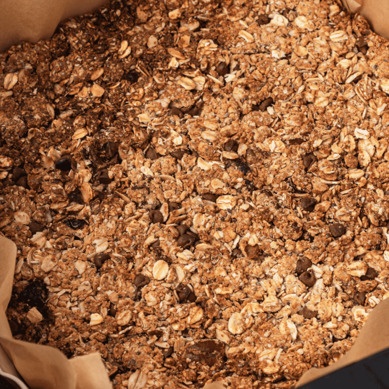 Crunchy granola clusters broken into chunks with chocolate and dried fruit added