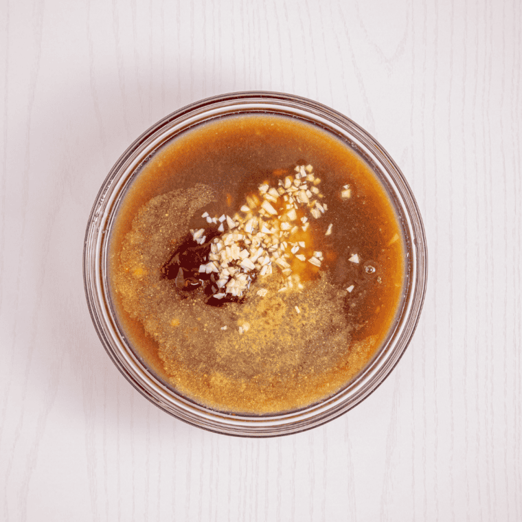 Whisking homemade Hawaiian tropical fruit marinade in a bowl until glossy
