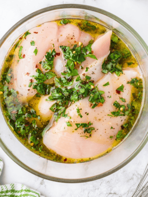 Raw chicken breasts marinating in copycat Lawry's lemon pepper marinade with fresh lemon slices