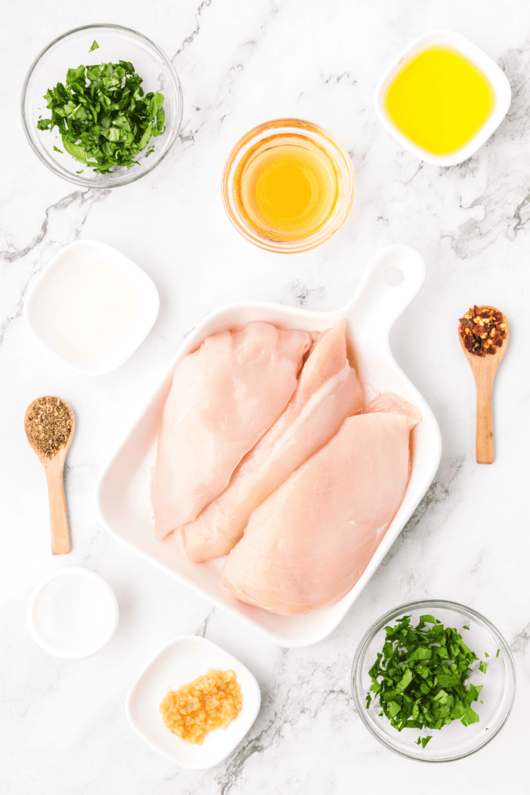 Copycat Lawry's lemon pepper marinade ingredients arranged on a table with fresh lemons, cracked pepper, garlic, and herbs