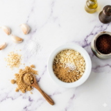 Homemade Lawry&rsquo;s seasoned salt blend in a small jar with spices scattered around.