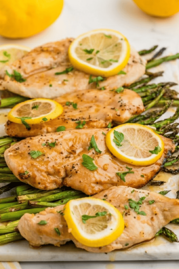 Lemon pepper seasoned chicken and roasted asparagus plated together, garnished with fresh lemon wedges