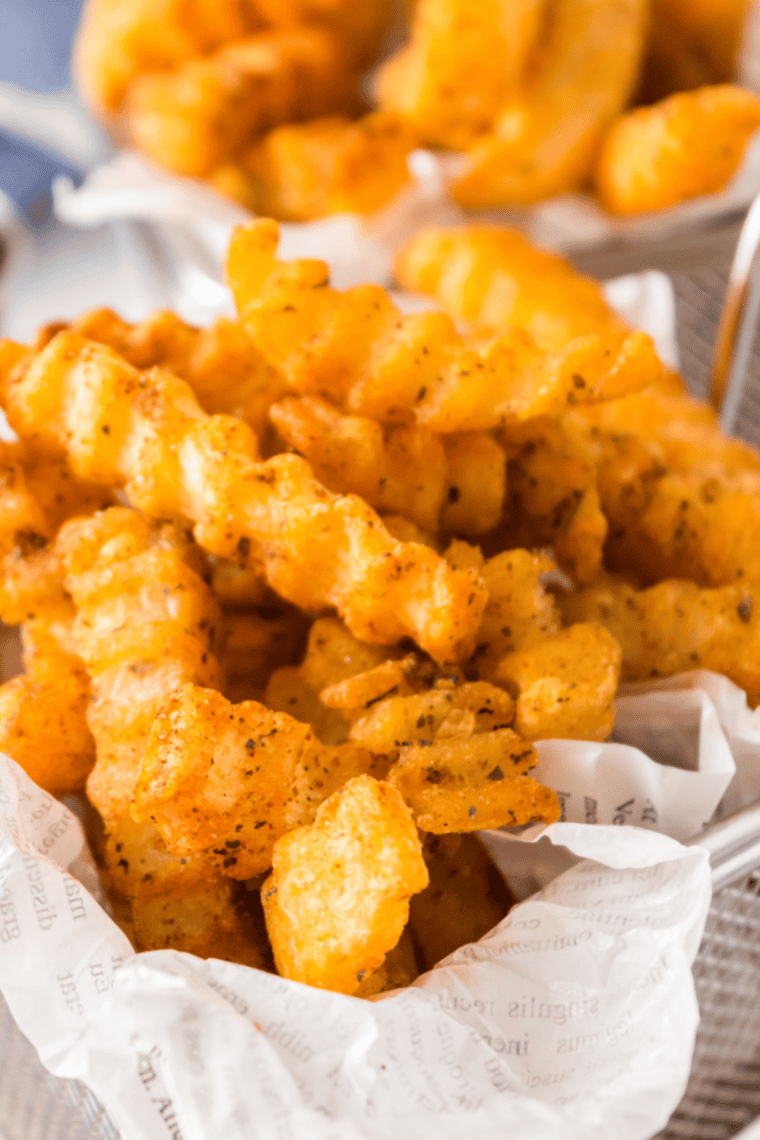 Golden french fries dusted with copycat Mrs. Dash seasoning in a paper cone