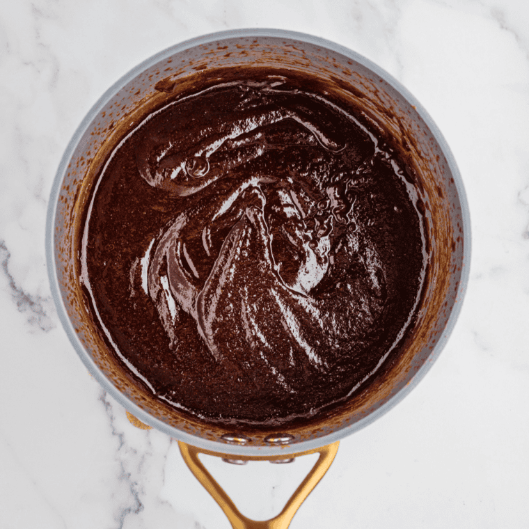Stubb's Original copycat barbecue sauce simmering and thickening in a saucepan, stirred with a spoon