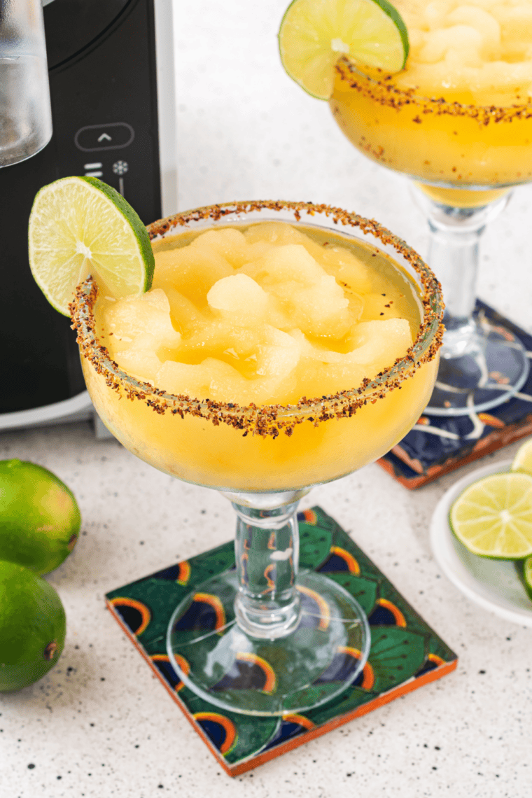 Mango margarita in a salt-rimmed glass garnished with a lime wedge