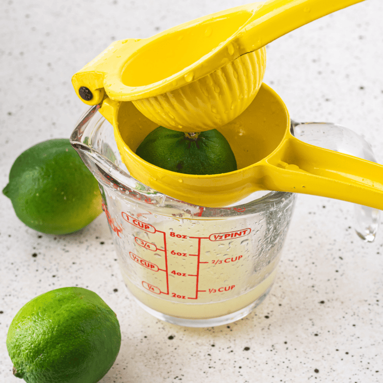 Fresh limes being squeezed into a jar for homemade margarita sour mix