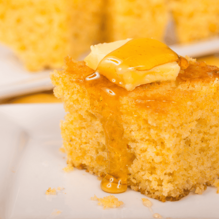Two squares of moist copycat Jason's Deli cornbread topped with butter