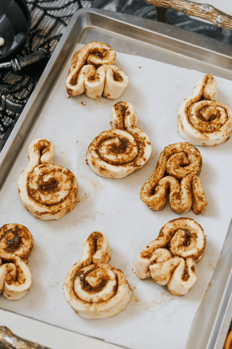 Parchment-lined baking sheet ready for Halloween cinnamon rolls with oven preheating to 350 degrees.