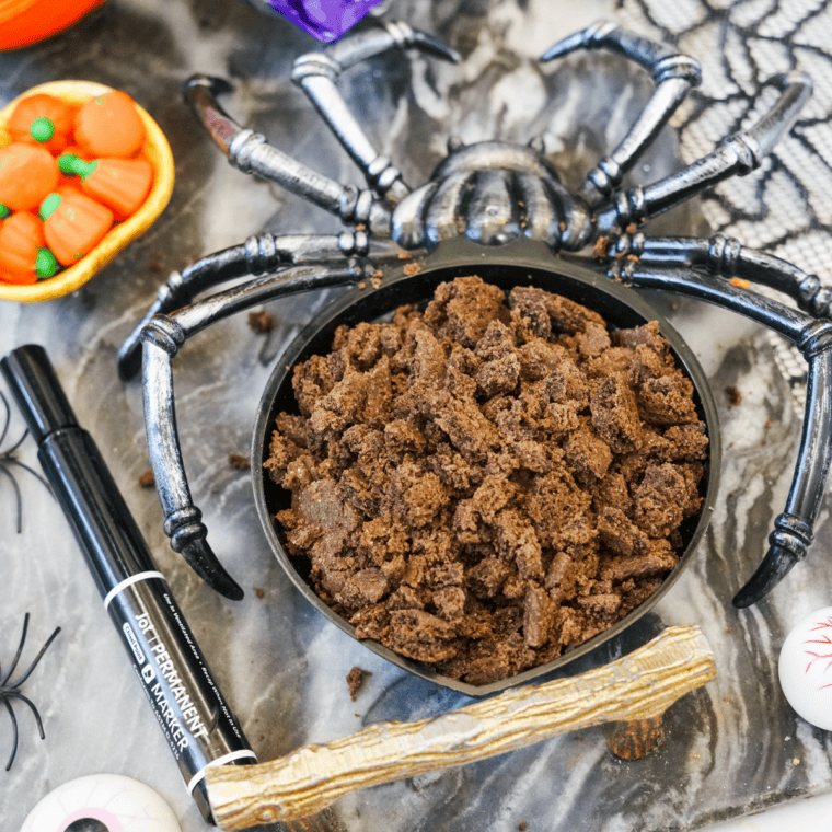 Crushed chocolate cookie crumbs sprinkled on top of pudding cups for Halloween pudding cups