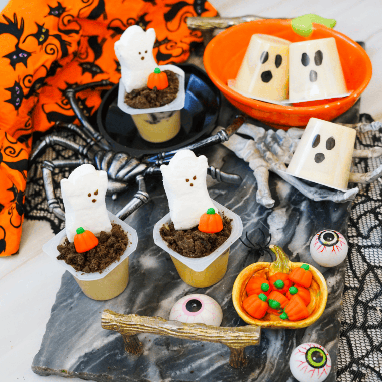 Finished Halloween pudding cups with hand-drawn ghost faces and spooky "boo" mouths