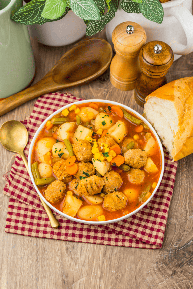 Hearty slow cooker meatball vegetable soup served in a white bowl with a spoon