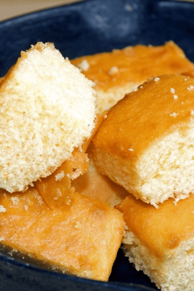 Two slices of golden homemade sweet cornbread with melting butter