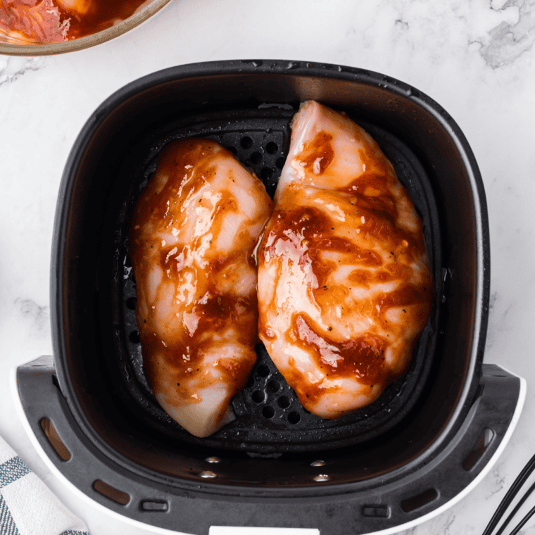 Seasoned chicken breasts cooking in a cast-iron skillet until golden and browned