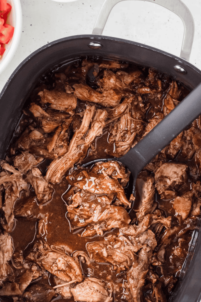 Fork pulling apart fork-tender pork shoulder cooked in the crock pot