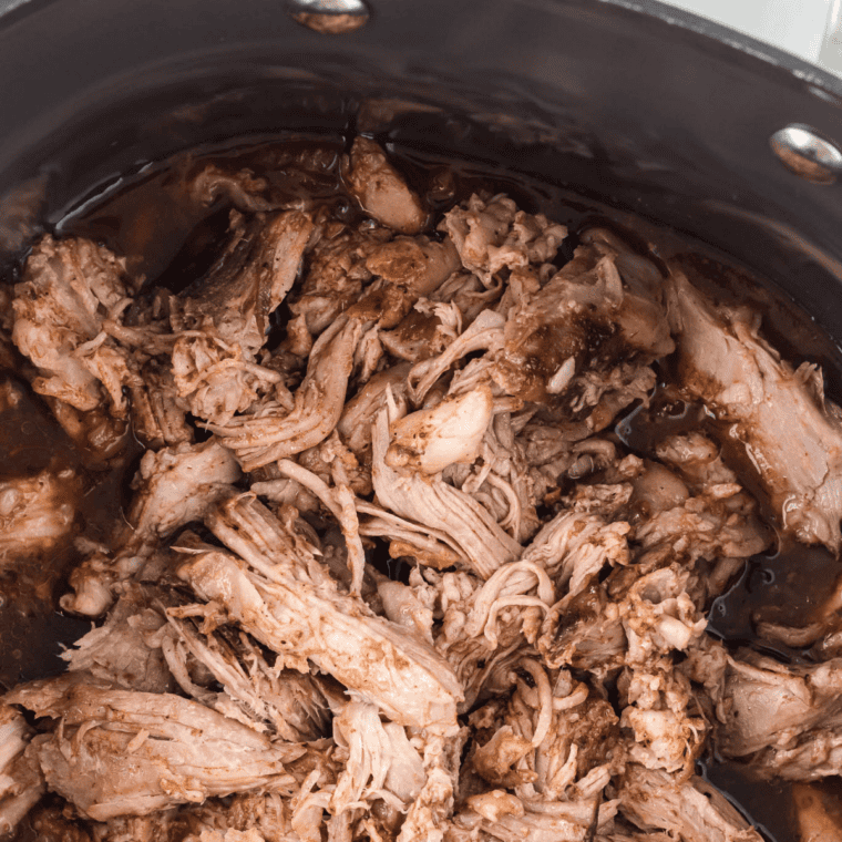 Fork pulling apart fork-tender pork shoulder cooked in the crock pot