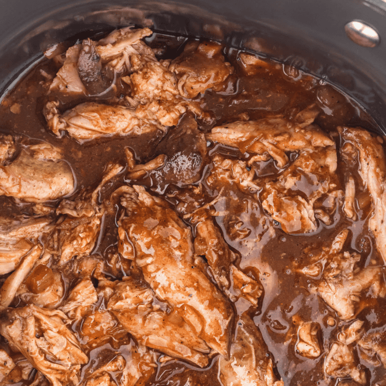 Shredded pulled pork tossed with glossy whiskey BBQ sauce in a bowl