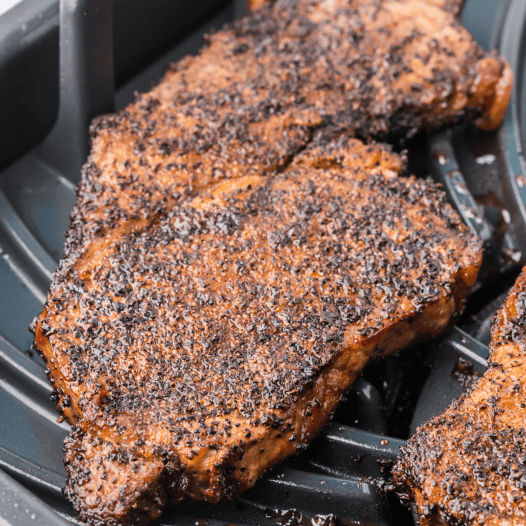 Jack Daniel's rib eye steak searing in a cast iron skillet with a glossy whiskey glaze and fresh thyme