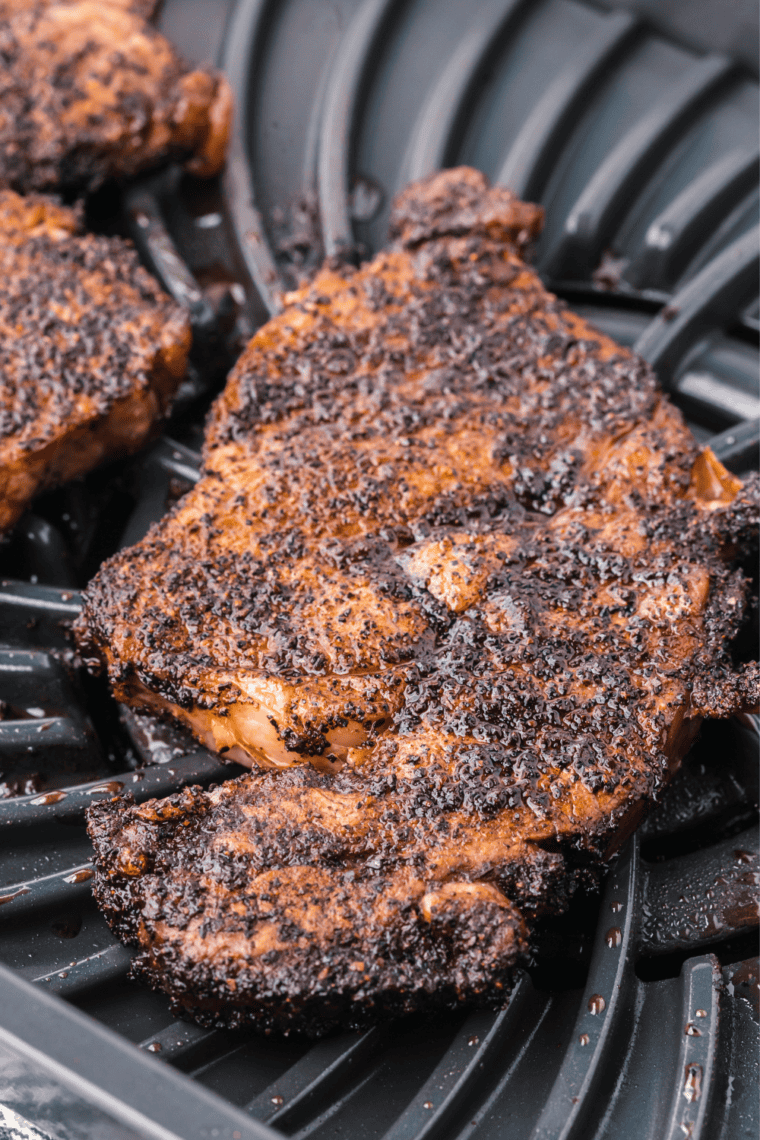 Brushing Jack Daniel's whiskey glaze over a seared rib eye steak in a cast iron pan