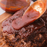 Jack Daniels meatloaf sliced on a wooden board, glazed with sticky whiskey BBQ sauce
