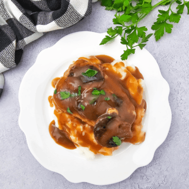 Copycat McCormick brown gravy poured over a bowl of creamy mashed potatoes