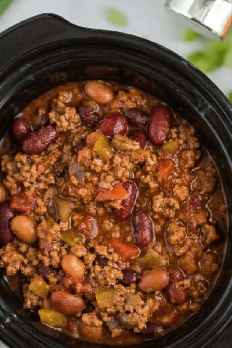 mccormick chili recipe in a crockpot cooking on low with steam rising