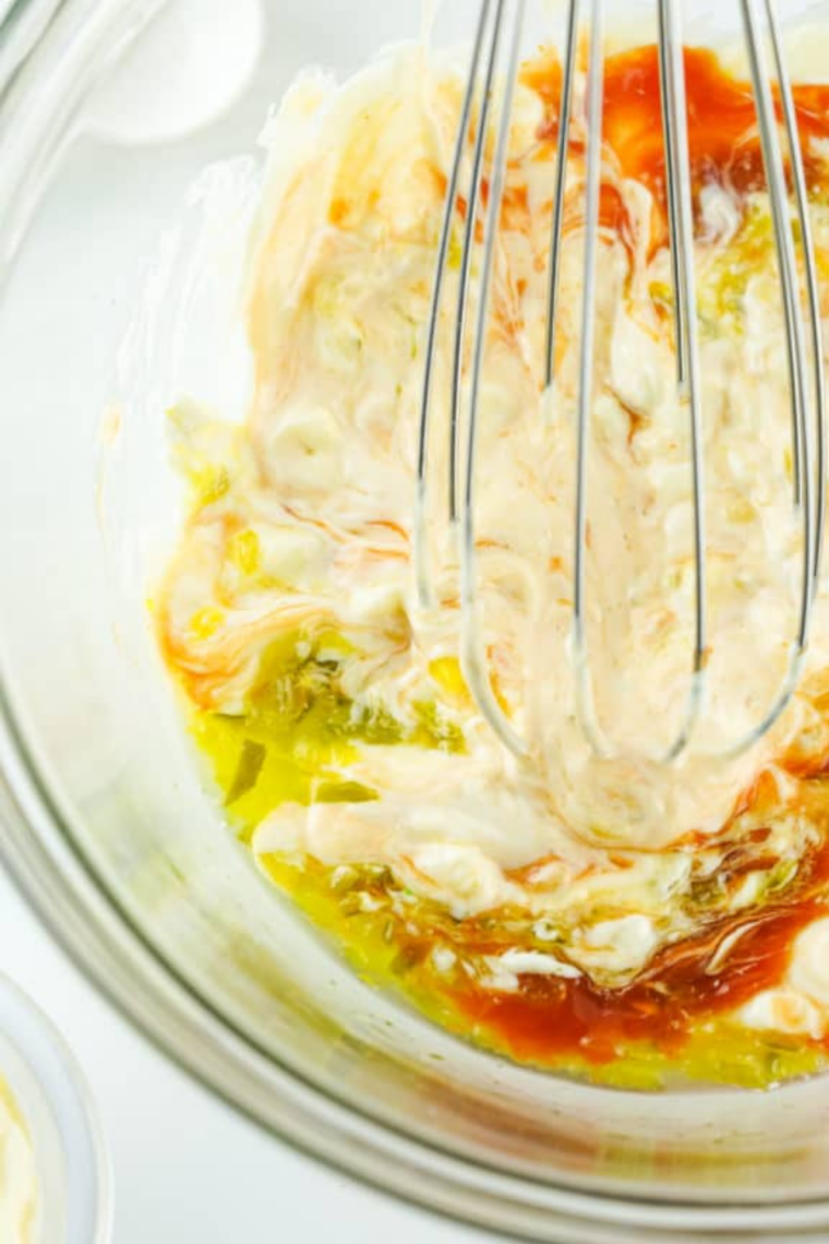 Mayonnaise, mustard, BBQ sauce, ketchup, honey, and vinegar added to a small white bowl to start the Signature Sauce.