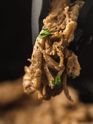 Slow cooker Mississippi pork roast shredded with pepperoncini peppers and buttery au jus in a crockpot