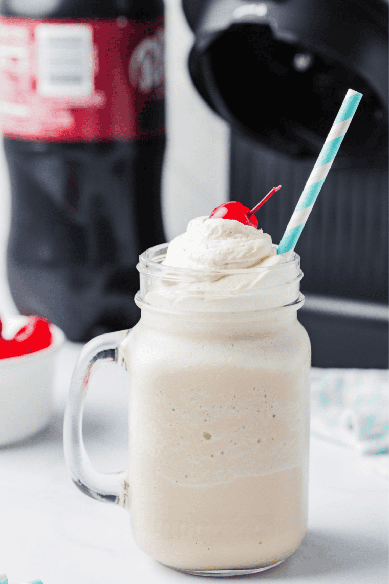 Creamy Ninja Creami pumpkin pie shake in a tall glass, topped with whipped cream and pumpkin spice