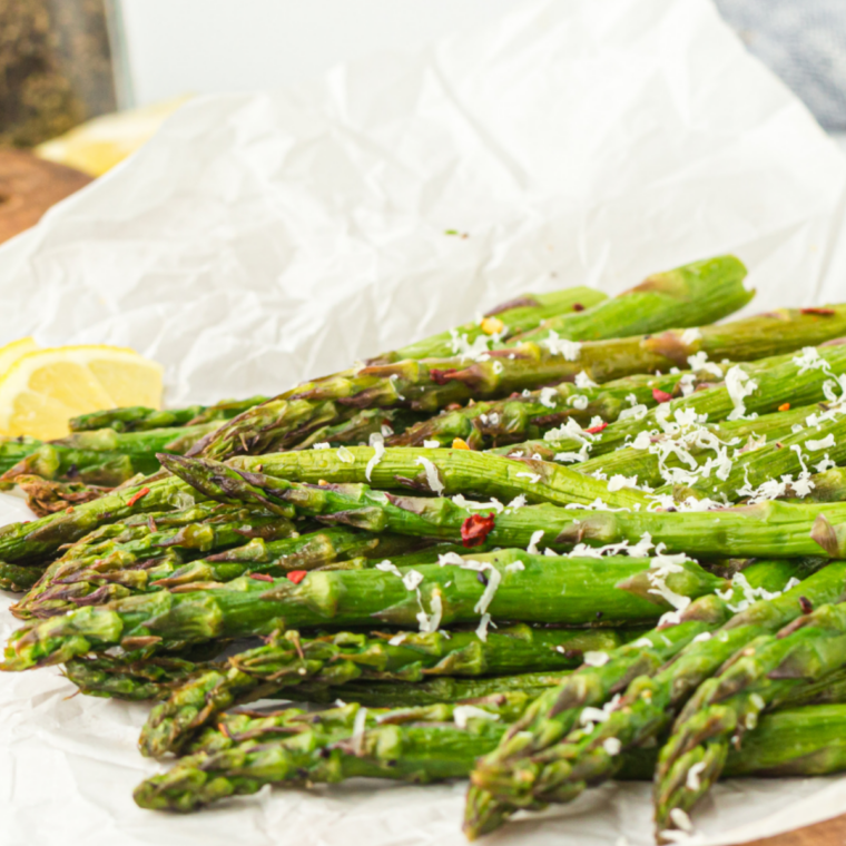 Hot asparagus topped with Parmesan cheese melting in Ninja Crispi during final air fry stage