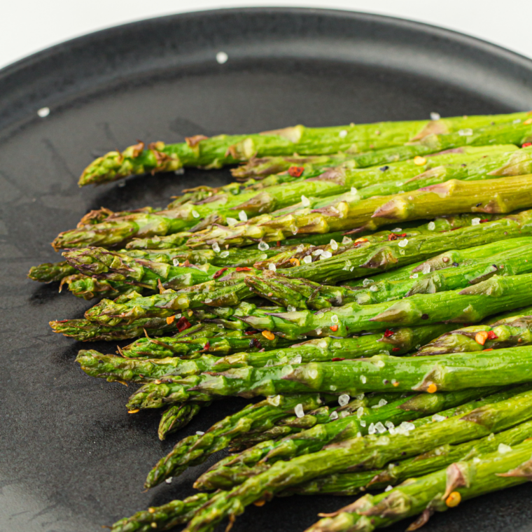 Ninja Crispi asparagus fresh from air fryer with golden crispy tips, Parmesan cheese, and lemon zest on top