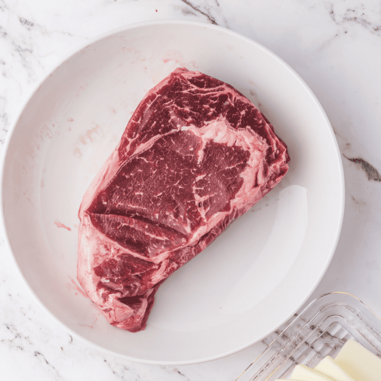 Cowboy Ribeye recipe ingredients: ribeye steak, butter, garlic, thyme, kosher salt and pepper