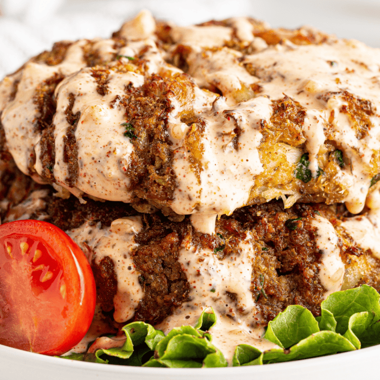 Ruth's Chris crab cakes on a bed of lettuce topped with remoulade sauce.