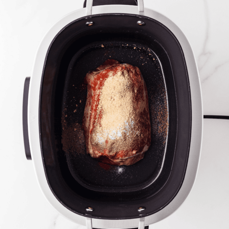 Pork shoulder being rubbed with brown sugar and smoked paprika spice blend