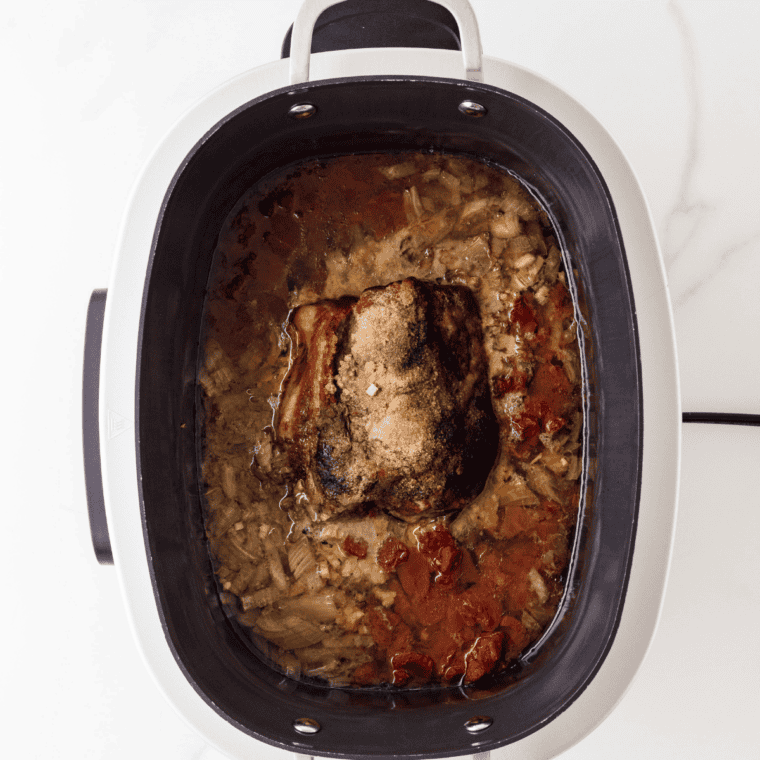 Cooked pork shoulder in a crockpot, tender enough to pull apart with a fork